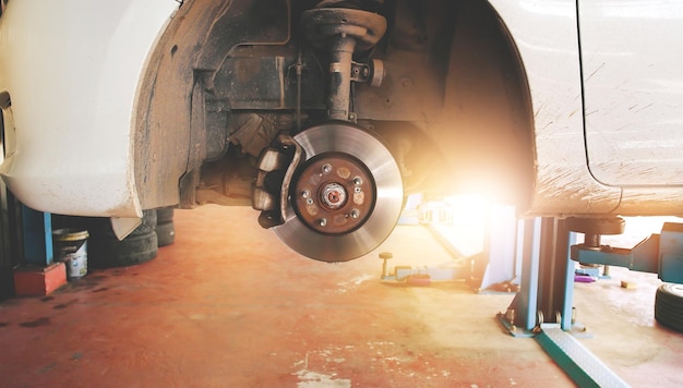 Freins à disque et étriers qui sans les roues d'une voiture dans le garage de réparation automobile avec la lumière du soleil