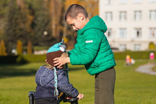 Un frère aîné met un chapeau sur son petit frère dans un parc de la ville par une chaude journée d'été