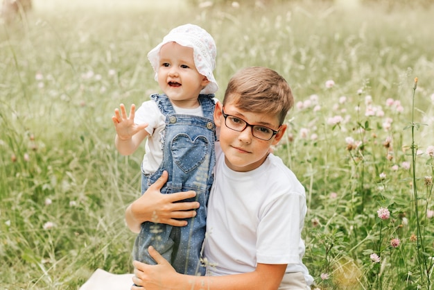 Le frère aîné tient la petite soeur en parc pendant l'été