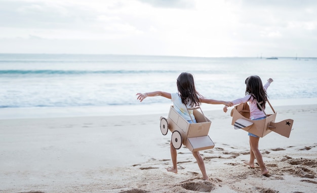 Frère et petite amie jouant avec un avion en carton et une voiture sur la plage