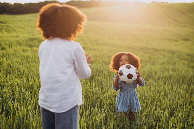 Frère et sœur jouant avec ballon sur le terrain