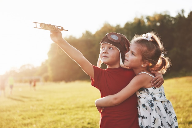 Frère et sœur jouent ensemble. Deux enfants jouant avec un avion en bois en plein air