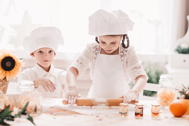 Le frère et la soeur préparent des biscuits dans la cuisine à la maison