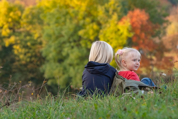 Frère et soeur s'amusent dans la nature Petit garçon et fille aux cheveux blonds jouent assis sur l'herbe dans le parc d'automne Vue arrière