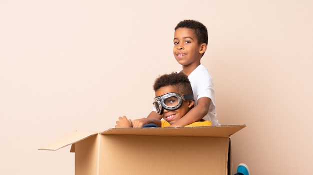 Frères afro-américains jouant. Garçon à l'intérieur d'une boîte en carton avec des lunettes d'aviateur