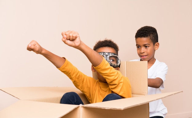 Frères afro-américains jouant. Garçon à l'intérieur d'une boîte en carton avec des lunettes d'aviateur