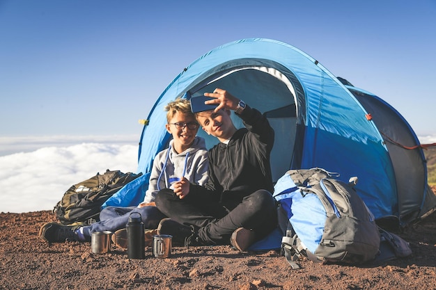 Des frères se font un selfie en camping sur la montagne.