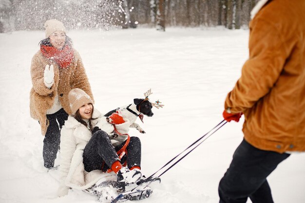 Frères et sœurs adolescents leur mère et chien noir sur un traîneau à winter park
