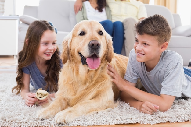 Frères et sœurs allongés avec un chien alors que les parents sont assis sur le canapé