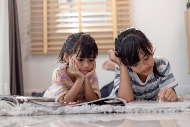 Des frères et sœurs concentrés en train de lire un livre.