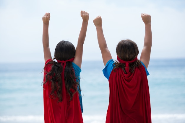 Frères et sœurs debout avec les bras levés au bord de la mer