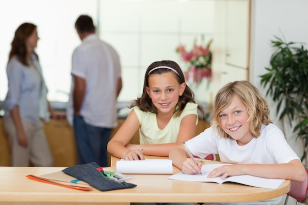 Les frères et sœurs font leurs devoirs avec leurs parents derrière eux