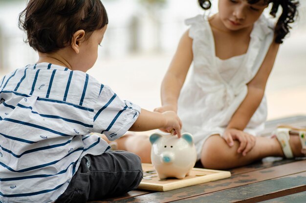 Des frères et sœurs insèrent des pièces dans la tirelire sur la table.