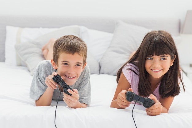 Frères et sœurs sur le lit en jouant à des jeux vidéo