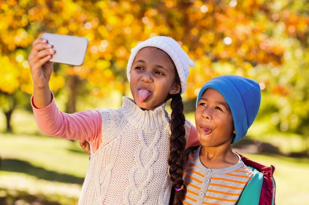 Frères et sœurs ludiques prenant selfie au parc