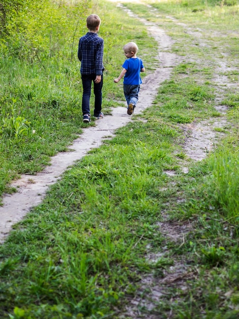 Des frères et sœurs marchant sur un sentier au milieu d'un champ herbeux