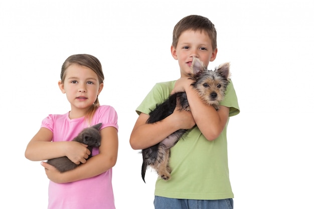 Frères et sœurs mignons tenant leurs animaux de compagnie et souriant à la caméra