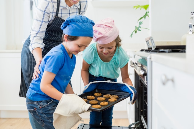 Frères Et Sœurs Plaçant Le Plateau De Biscuits Dans Le Four