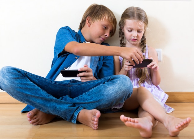 Frères et sœurs positifs jouant avec des téléphones