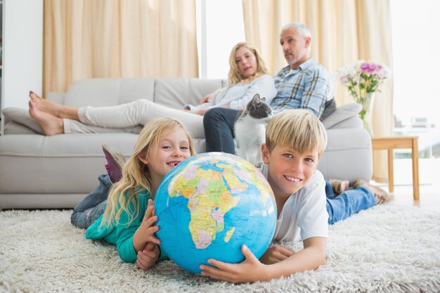 Frères et sœurs regardant le globe sur le sol