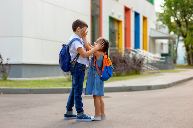 frères et sœurs avec des sacs à dos se touchant le visage