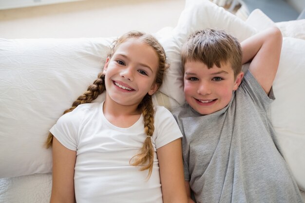 Frères et sœurs se détendre sur le lit dans la chambre