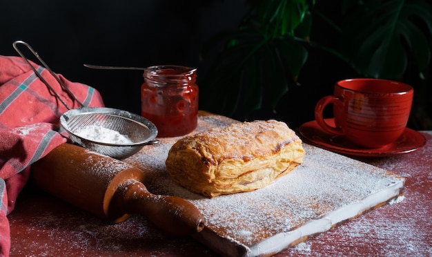 Fresh Puff garni de prune ou de confiture de groseille rouge sur la table avec une tasse rouge et pot de confiture sur le fond noir.