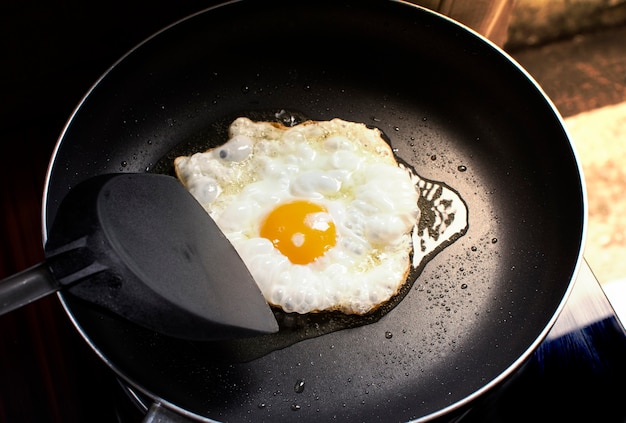 Fried côté ensoleillé oeuf dans une poêle noire et bêche en plastique