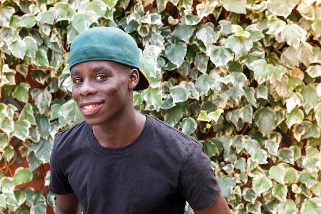 Friendly smiling black guy contre le feuillage vert