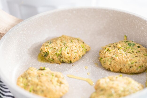 Frire les galettes de courgettes dans l'huile d'olive sur une poêle.