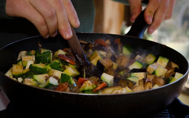 frire les légumes dans le wok en cuisinant avec une cuillère en bois