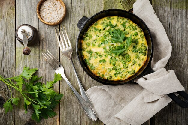 Fritatta Aux Pommes De Terre, Pois Verts Et Herbes Dans Une Poêle En Fer Sur Un Vieux Fond En Bois