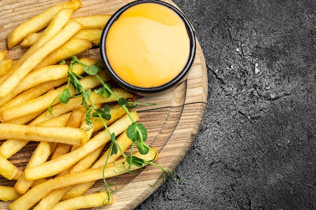 Frites chaudes fraîches avec sauce au fromage sur fond de béton foncé Menu du restaurant recette de livre de régime vue de dessus