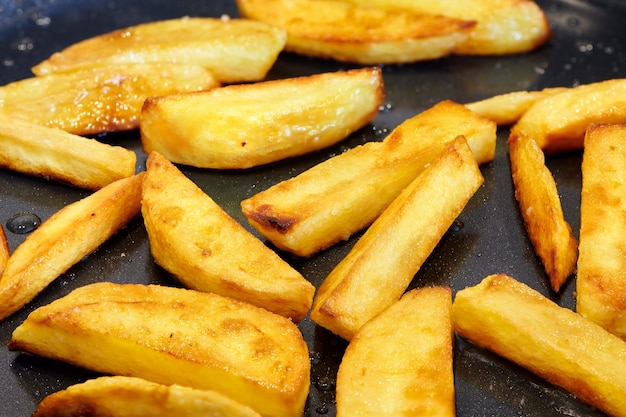 Frites croustillantes et dorées. Chips frites maison. Faire frire la pomme de terre à la poêle. Fond de cuisson des aliments. Vue rapprochée.