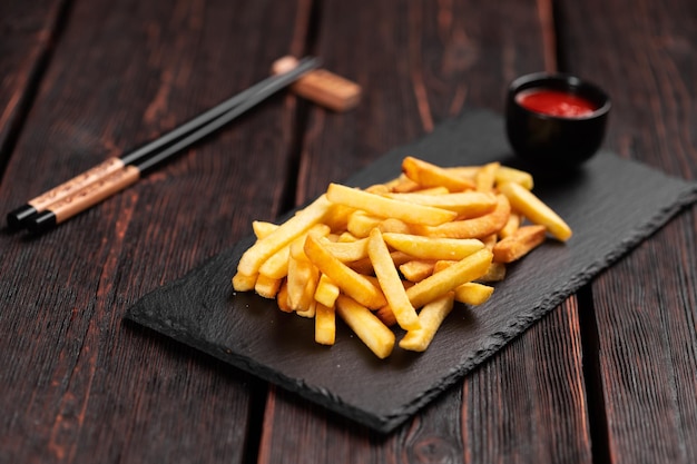 Frites avec du ketchup sur fond de bois foncé restauration rapide et concept de mauvaise alimentation