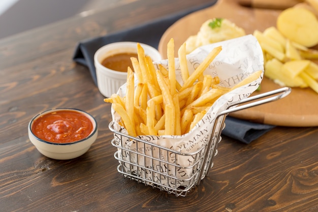 Frites avec du ketchup sur fond de bois.