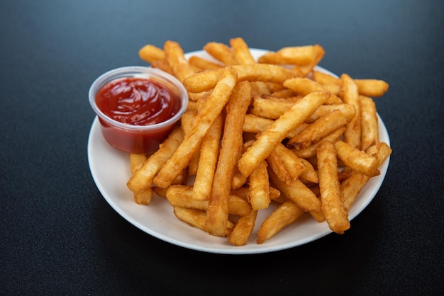 Frites avec du ketchup sur la vue latérale de fond sombre