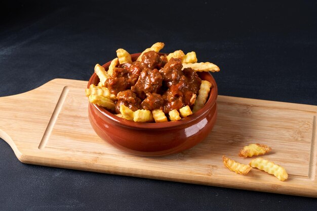 Frites frites au goulasch dans une assiette rouge