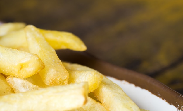 Frites frites sur une plaque blanche avec bordure brune sur la table en bois