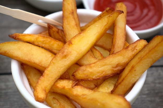 Frites maison dans des bols pour les collations et les sauces sur fond de bois.