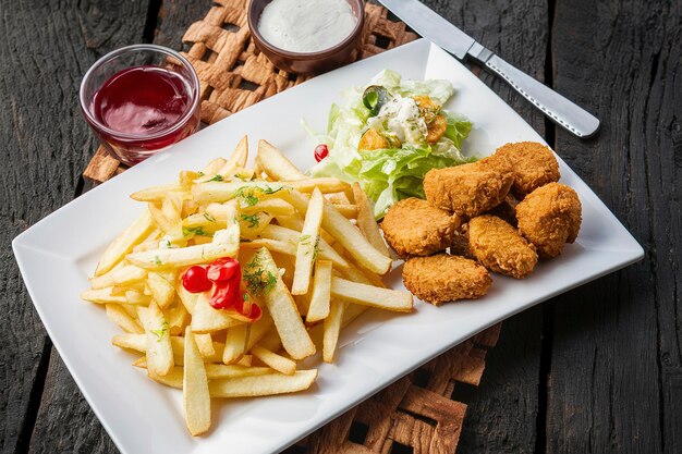 Des frites avec des nuggets de poulet et de la salade