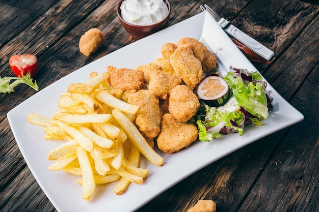 Des frites avec des nuggets de poulet et de la salade