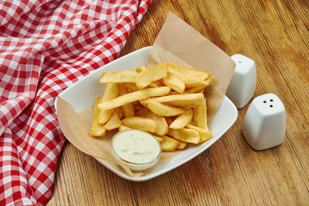 Frites en papier kraft sur plaque grise sur bois. Restauration rapide traditionnelle américaine.