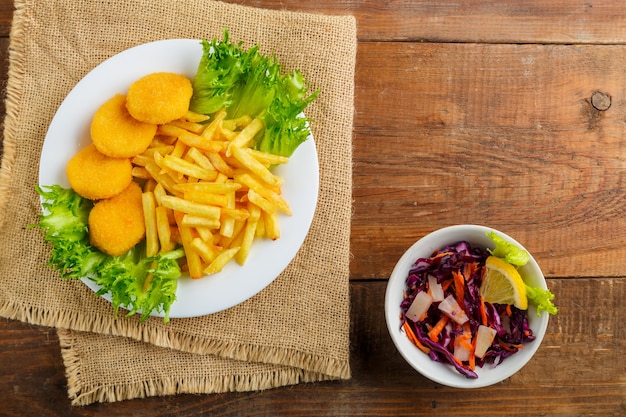 Frites avec pépites de poulet près de cole slow sur une serviette sur une table en bois. photo horizontale