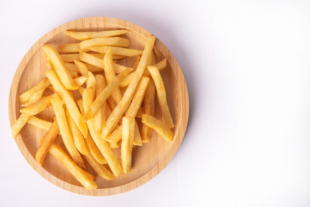 Frites placées sur une assiette en bois ronde, vue du dessus.