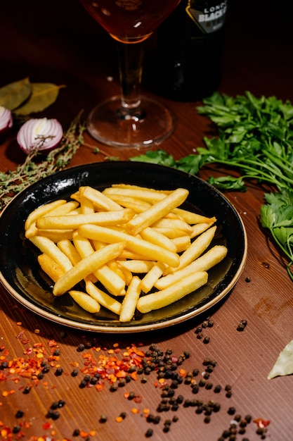 Frites sur plat noir sur fond de bois.