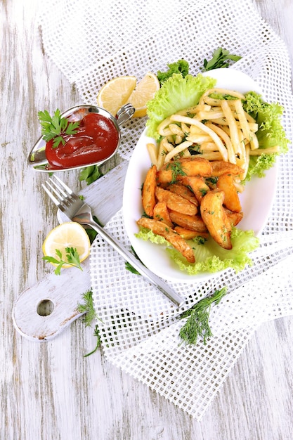 Frites et pommes de terre maison sur plaque à bord sur serviette sur table en bois