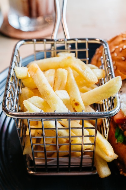 Photo frites servies dans un panier en acier pour manger avec un hamburger.