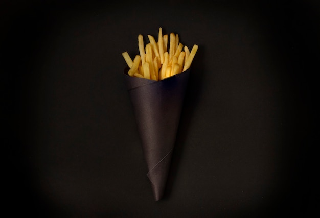 Photo frites sur une table noire, dans un emballage noir, horizontal