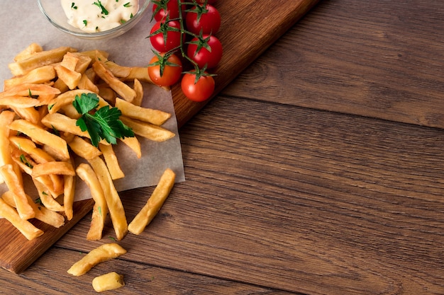 Frites, tomates cerises, sauce à l'ail sur bois